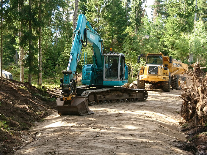 Dumper och grävmaskin vid nybyggd väg